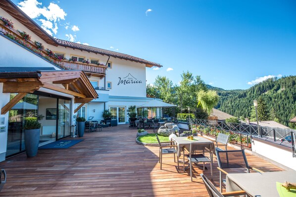 A hotel with a wooden deck, outdoor seating, and a mountain view. - Hotel Marica (Nova Ponente)