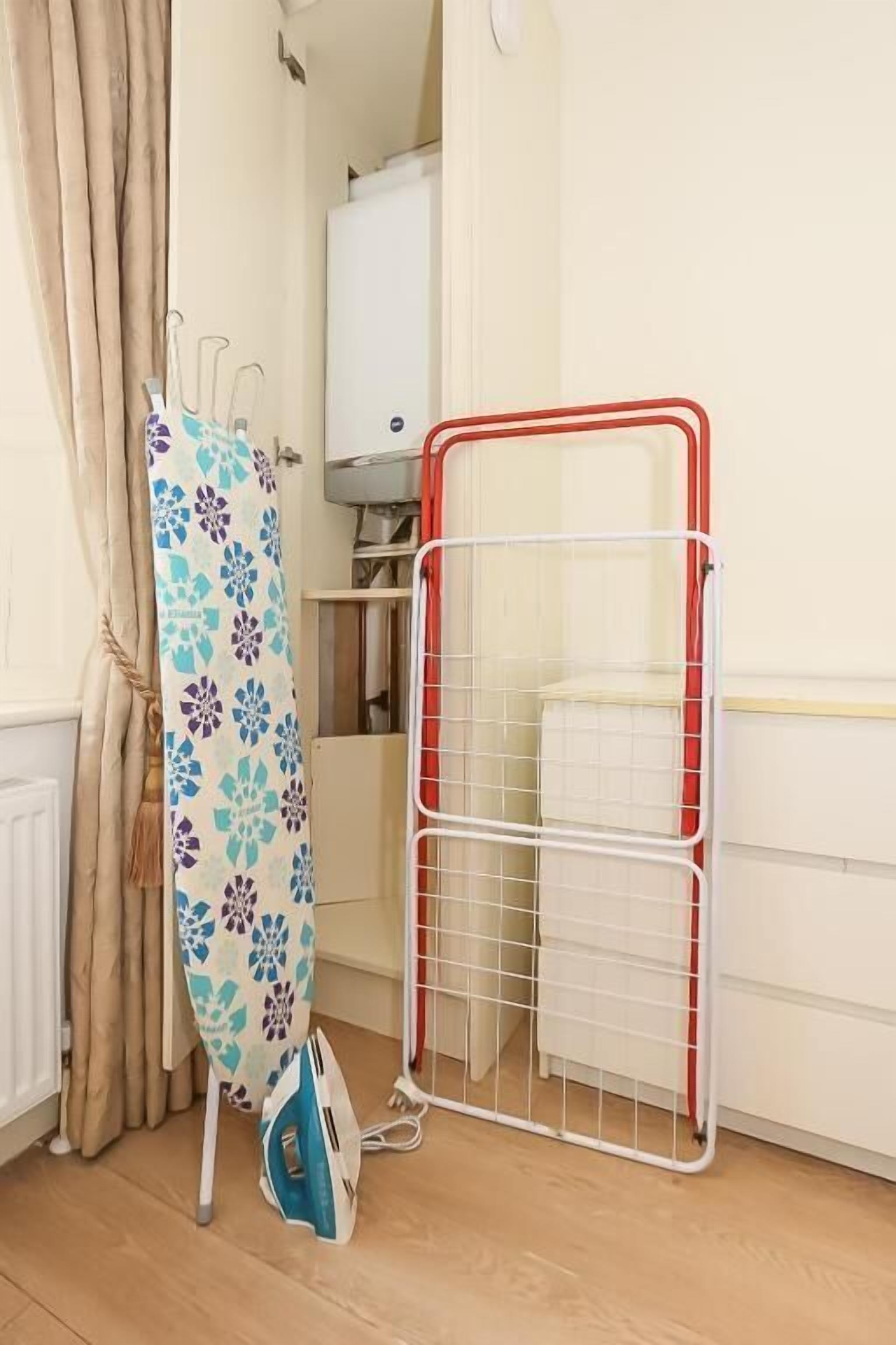 Ein Zimmer mit einer Wäscheständer, einem Bügelbrett aus Metall und einem weißen Schrank.