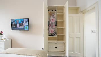 A bedroom with a bed, a TV mounted on the wall, and a walk-in closet with shelves and hanging space.