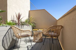 A small outdoor seating area with wicker chairs and a round table, surrounded by potted plants. - Hotel Oasis (Barcelona)