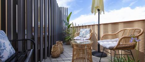 A deck with wicker furniture, a bench, and a potted plant.