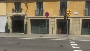 Fachada de hotel com o letreiro "HOTEL OASIS", placa de proibição de estacionamento e faixa de pedestres.