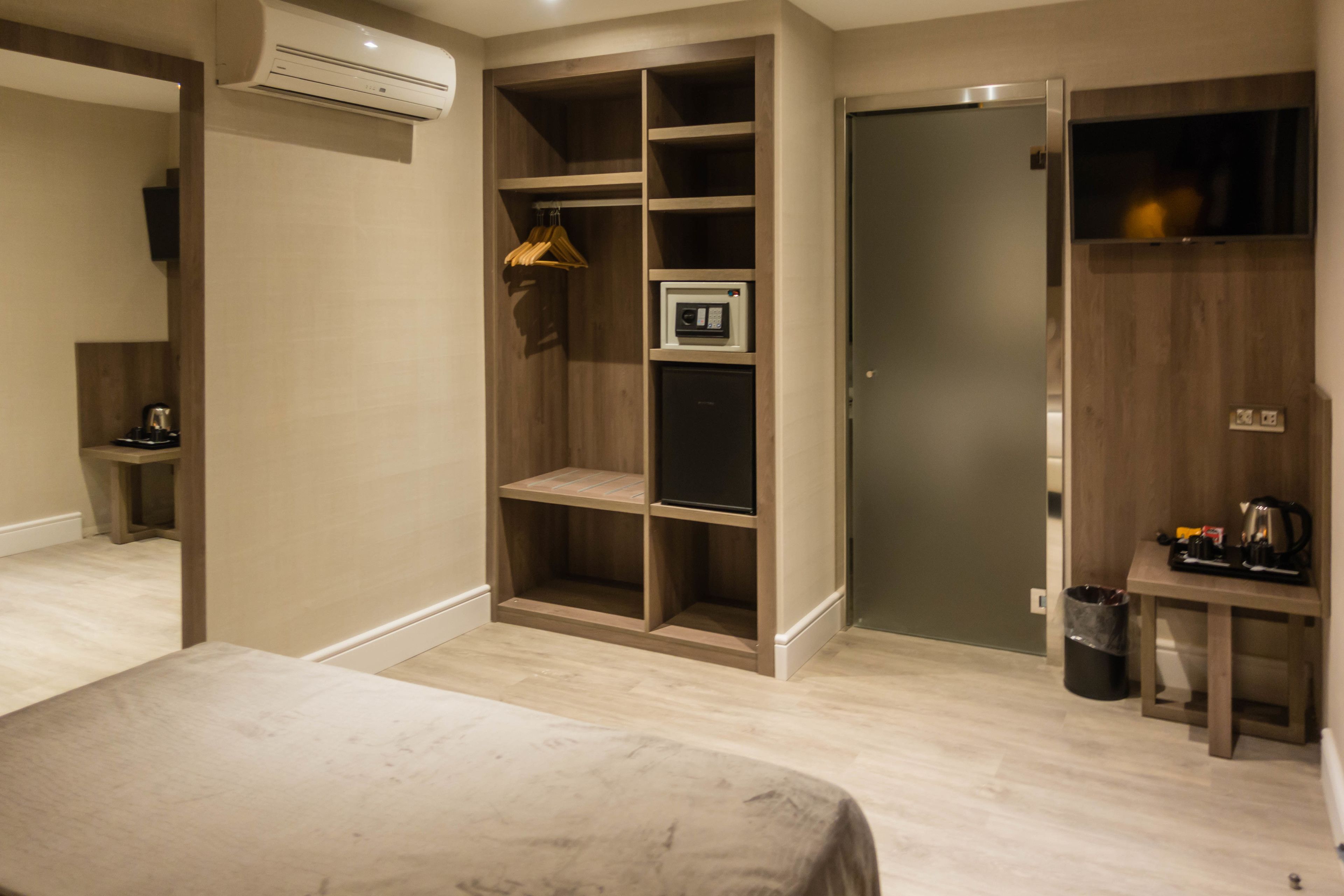 Hotelkamer met een bed, een inbouwkleerkast, een tafeltje met waterkoker en een prullenbak.