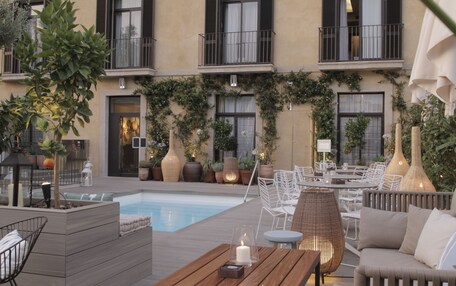 A rooftop pool area with outdoor seating and potted plants.