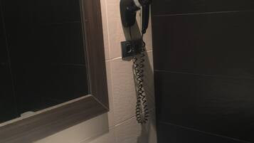 Une salle de bain équipée d’un lavabo, d’un sèche-cheveux fixé au mur et d’un miroir.