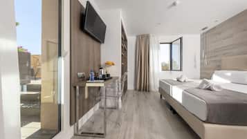 A modern hotel room with a bed, a desk with a chair, a TV mounted on the wall, and a large window with curtains.