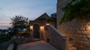 A stone building with a staircase and arched entrance, illuminated by warm lighting. - Villa Larsen (Omis)