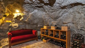 A cozy room with a red sofa, wooden wine racks, and stone walls. - Villa Larsen (Omis)