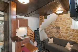 Un espacio habitable pequeño con una pared de piedra, una escalera de madera y un sofá.