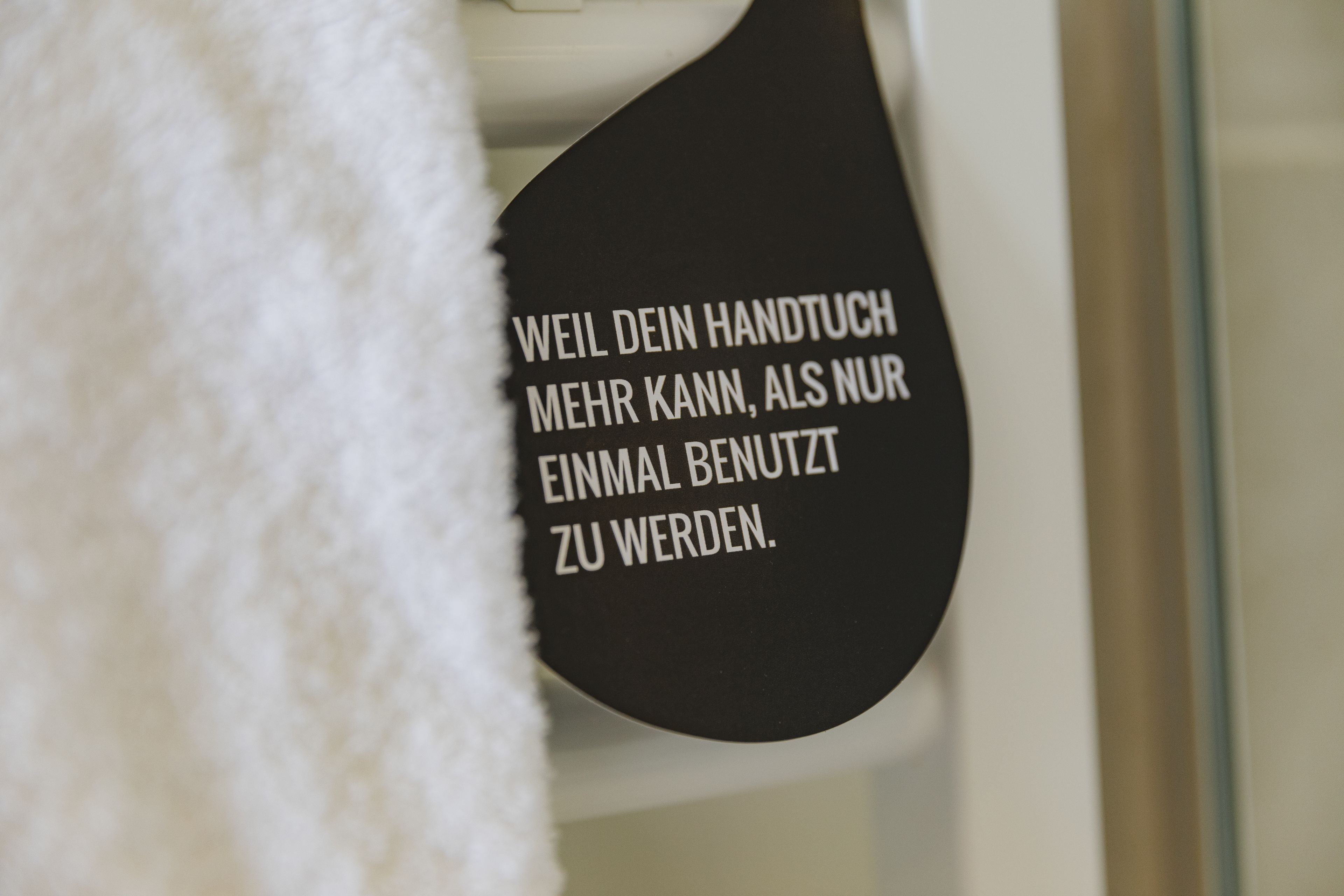 A black sign with white text in a bathroom.