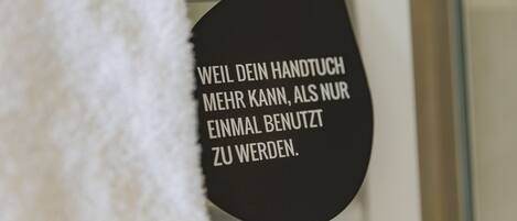 A black sign with white text in a bathroom.