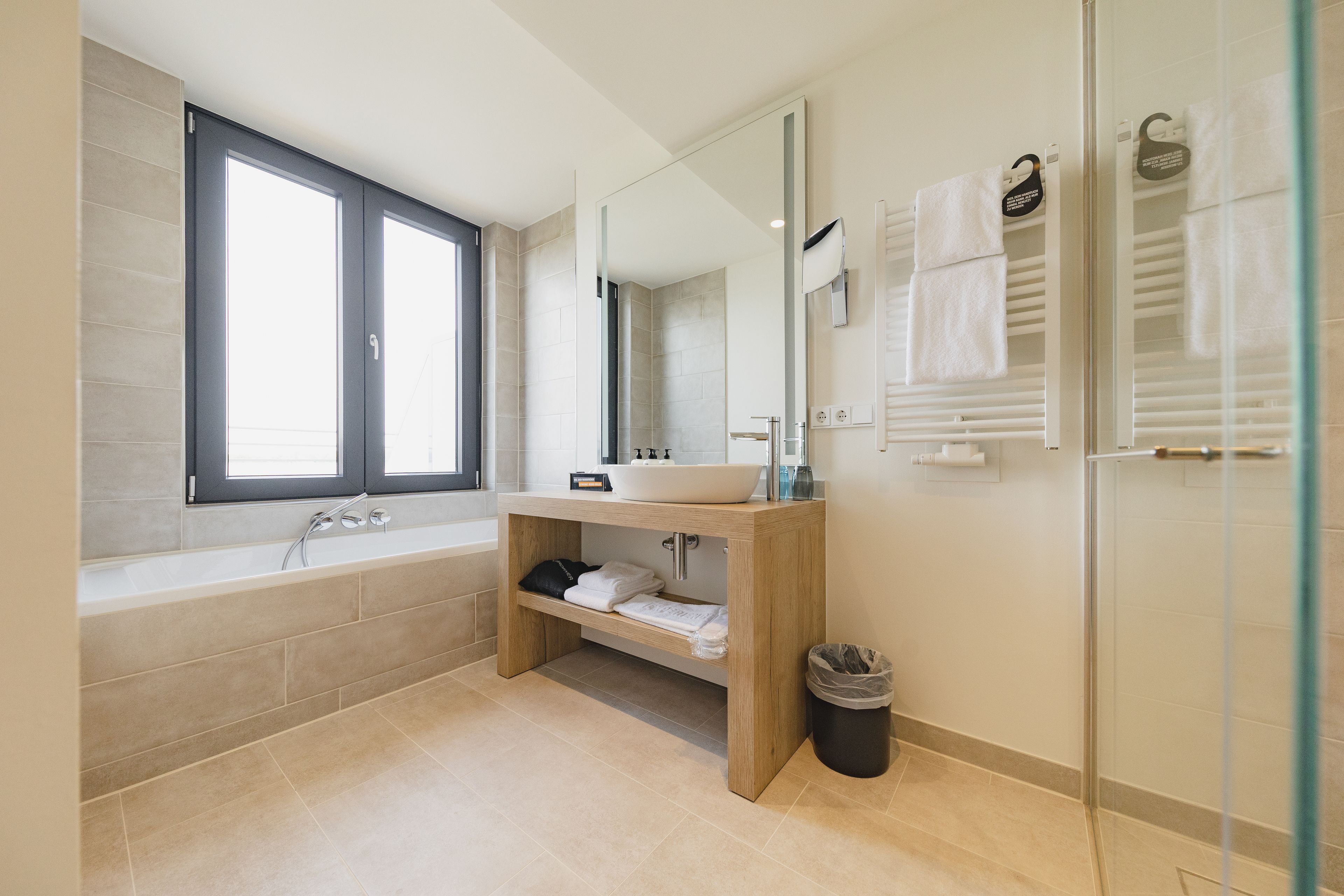 A modern bathroom with a bathtub, a sink, a mirror, and a glass shower enclosure.