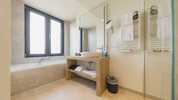 A modern bathroom with a bathtub, a sink, a mirror, and a glass shower enclosure.