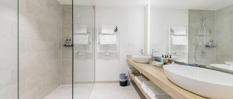Une salle de bain moderne avec deux lavabos, une douche en verre et un miroir.