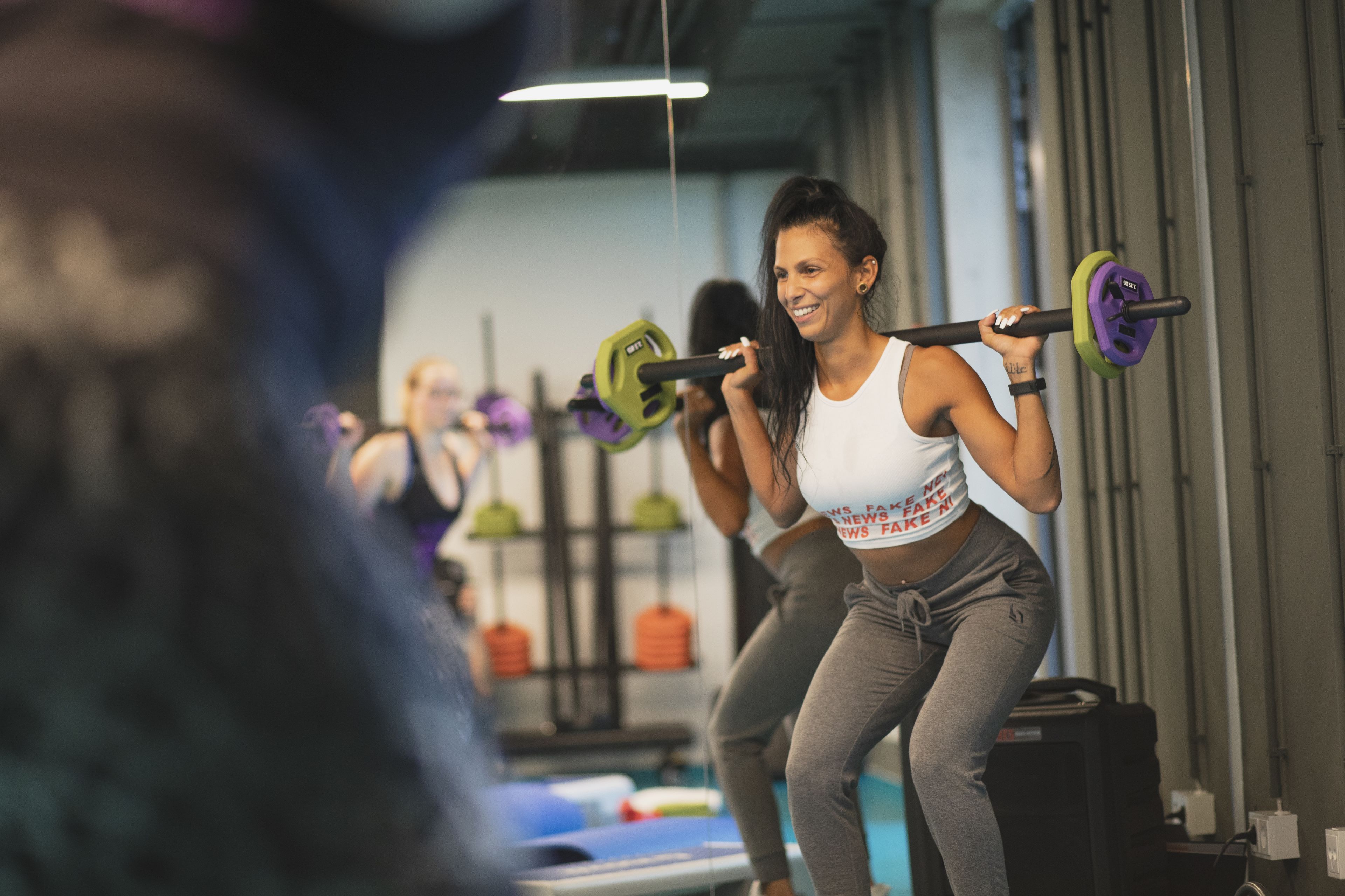 Ein Fitnessraum mit Gewichteinrichtungen und einer Person, die Kniebeugen macht.