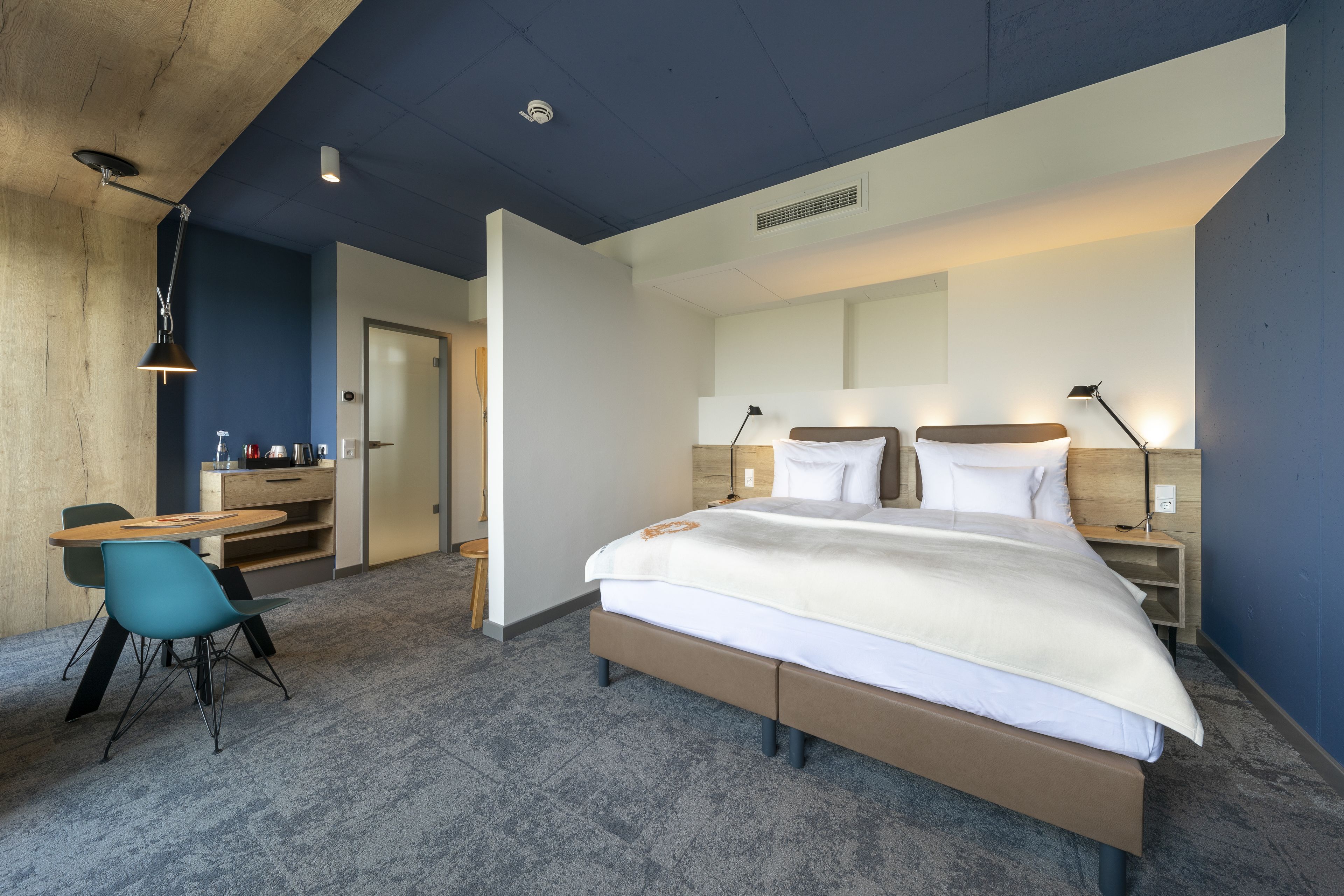 Una habitación de hotel moderna con una cama grande, un escritorio con una silla y una mesita.