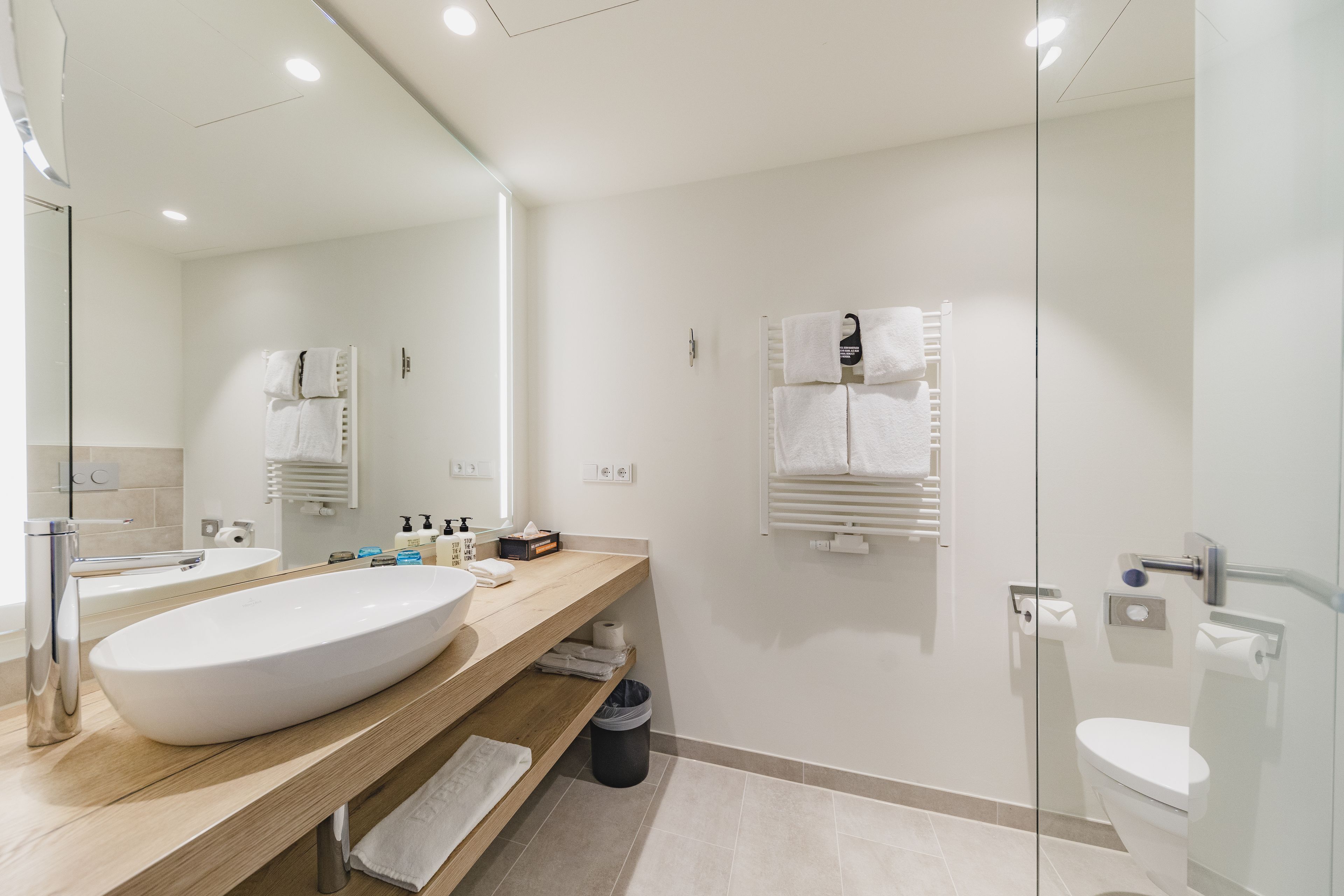 Un baño moderno con un lavamanos grande, un espejo, un inodoro y una zona de ducha.