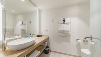 Un baño moderno con un lavamanos grande, un espejo, un inodoro y una zona de ducha.