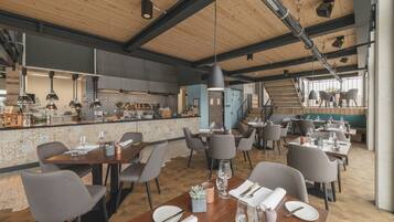 A modern restaurant with wooden ceilings, a bar area, and multiple dining tables with chairs.