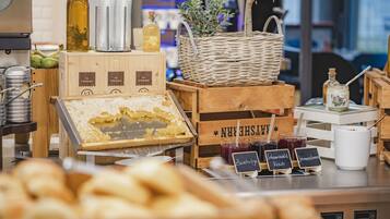 Una vitrina de panadería con diversos productos horneados, un cesto de madera con la etiqueta 'NEW CHESHREN' y una cesta de mimbre.