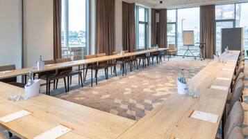 A conference room with long tables, chairs, a projector, and a whiteboard.