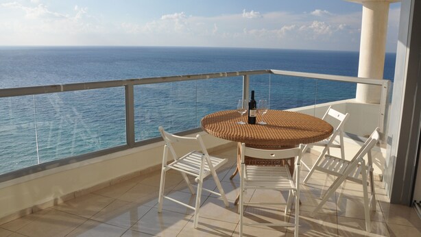 A balcony with a round table, white chairs, and a bottle of wine. - Isra Home Luxury Apartment with Sea View (Bat Yam)