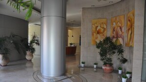 A lobby with a large pillar, a reception desk, and several potted plants. - Isra Home Luxury Apartment with Sea View (Bat Yam)