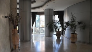 A spacious lobby with high ceilings, large columns, and potted plants. - Isra Home Luxury Apartment with Sea View (Bat Yam)