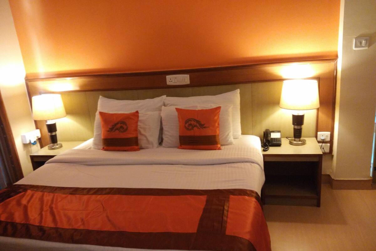 Ein Hotelzimmer mit einem Bett, zwei Nachttischen, zwei Lampen und einem Telefon auf einem der Tische.