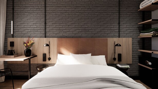 A modern hotel room with a brick wall, a wooden headboard, a bedside table with a lamp, and a nightstand with a book and a phone. - Hotel Transit (Barcelona)
