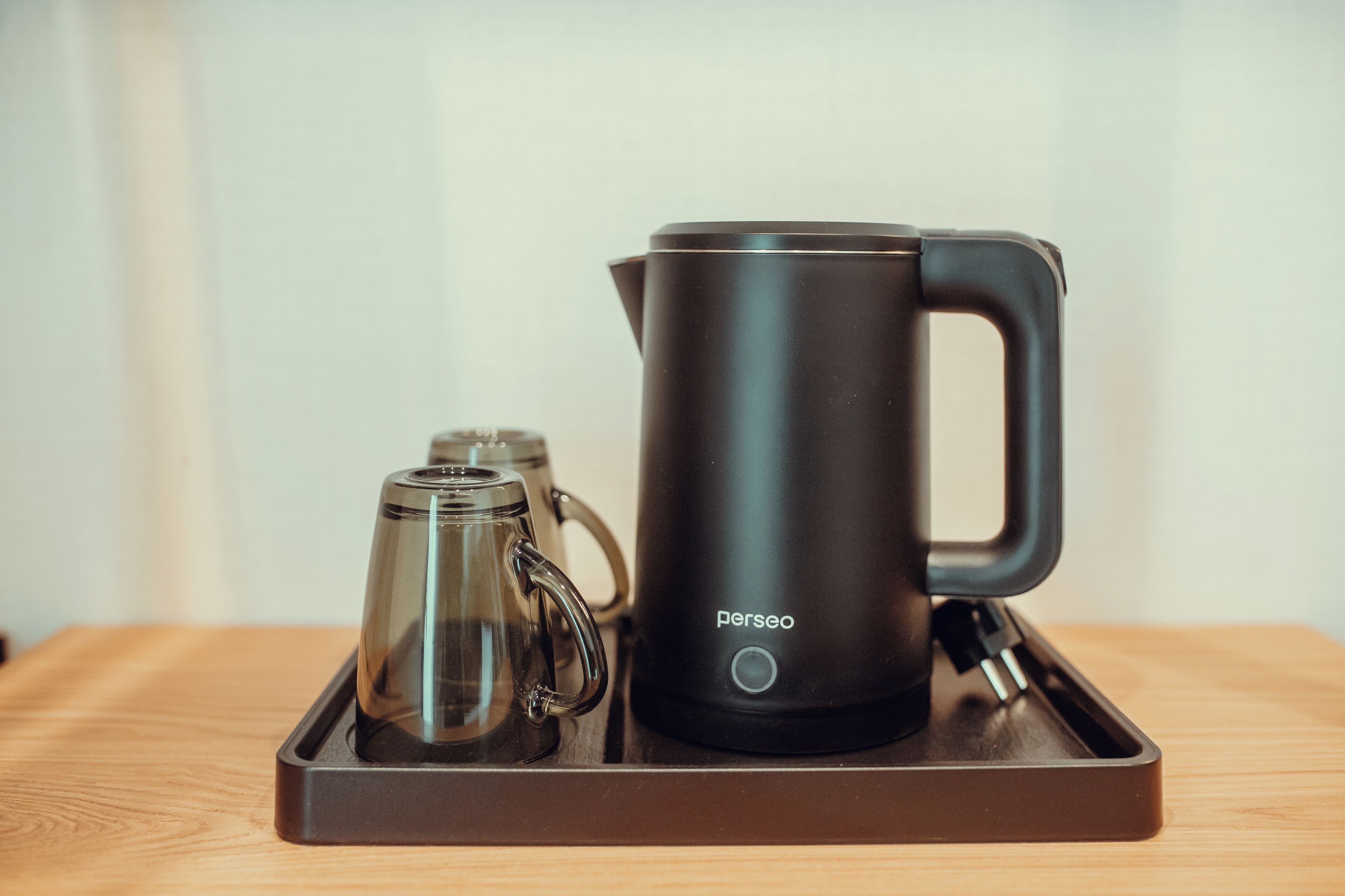 A black coffee maker and a glass carafe on a tray.