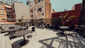 An outdoor patio with tables and chairs, surrounded by buildings. - Hotel Transit (Barcelona)