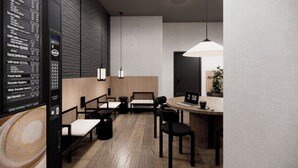 A modern cafe with a wooden floor, black and white furniture, and a digital clock displaying 2:58. - Hotel Transit (Barcelona)