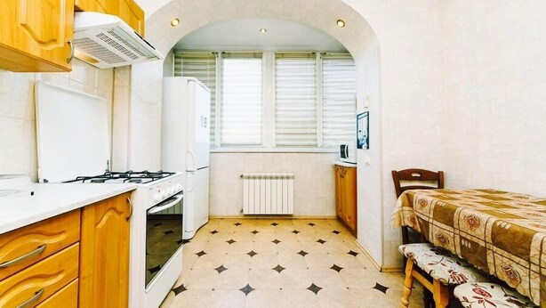 A compact kitchen with a stove, oven, and a window with blinds.