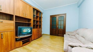 A living room with wooden cabinets, a television, and a beige sofa.