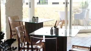 Un coin repas avec une table en verre, des chaises transparentes et des plantes en pot.