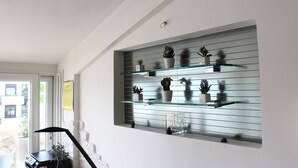 Un intérieur moderne avec une étagère en verre où sont exposées des plantes en pot et des objets décoratifs.
