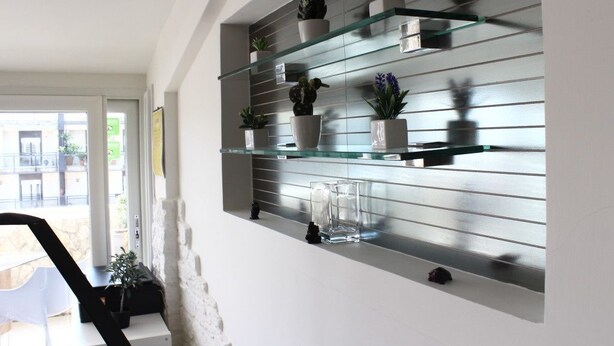 Un intérieur moderne agrémenté d’une étagère en verre où sont exposées différentes plantes en pot.