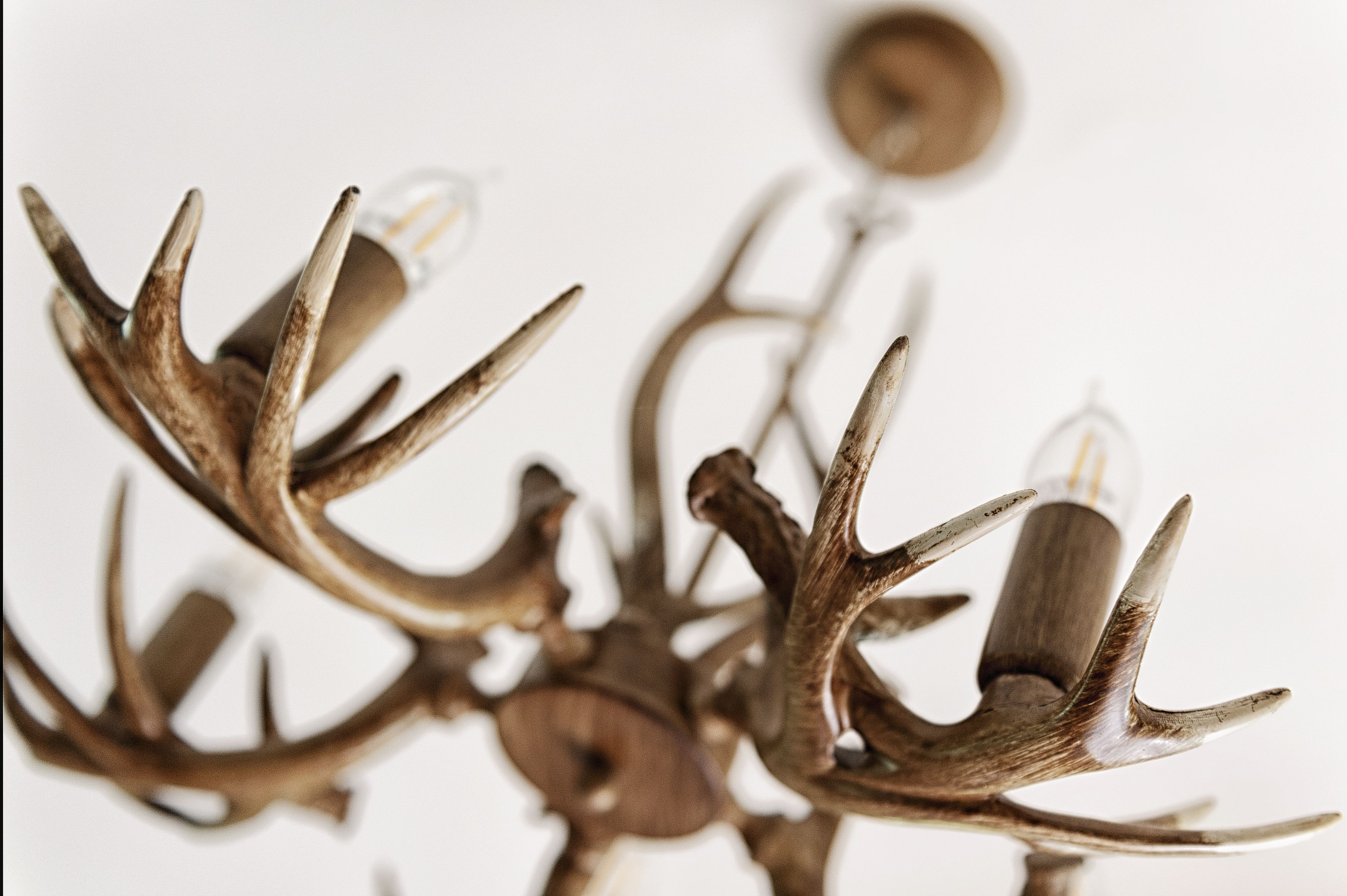 A chandelier with antler branches and light bulbs.