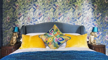 Uma cama com colcha azul, travesseiro colorido e cabeceira azul.