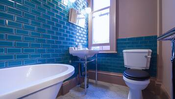 A bathroom with a white bathtub, a white sink, and a white toilet against a blue-tiled wall.