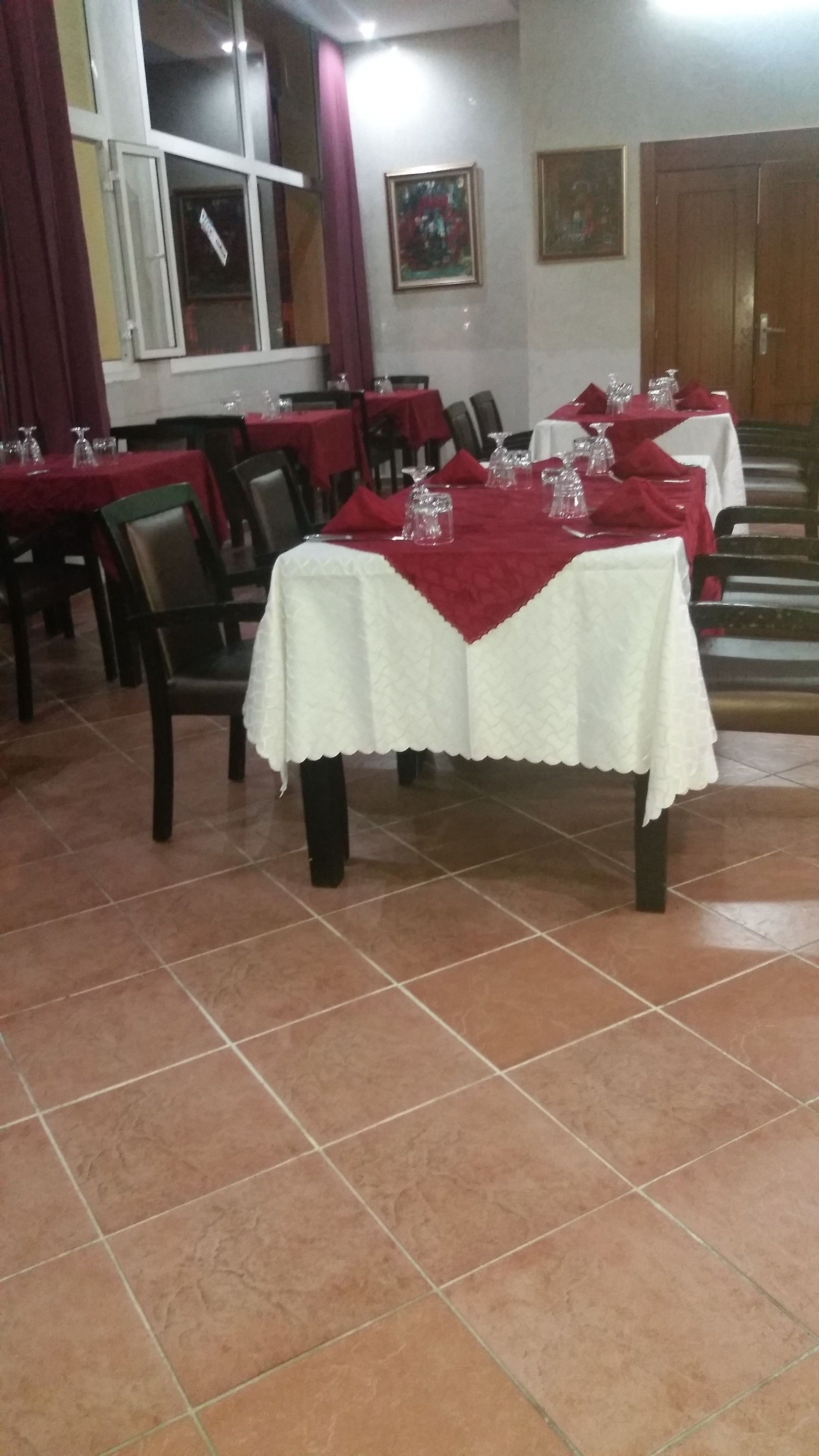 A dining area with tables set for service, chairs, and a tiled floor.