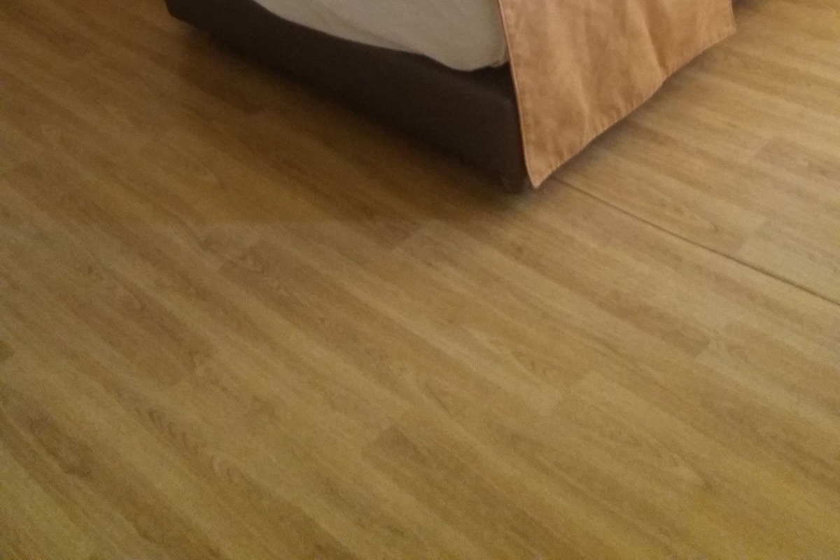 Habitación de hotel con dos camas, cada una con cabecera marrón, ropa de cama blanca y una lámpara sobre una mesita de noche.