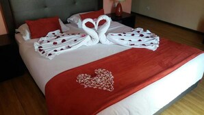 Cama bem arrumada com manta vermelha e um enfeite em formato de coração na colcha.