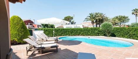 A swimming pool with lounge chairs and a pergola.