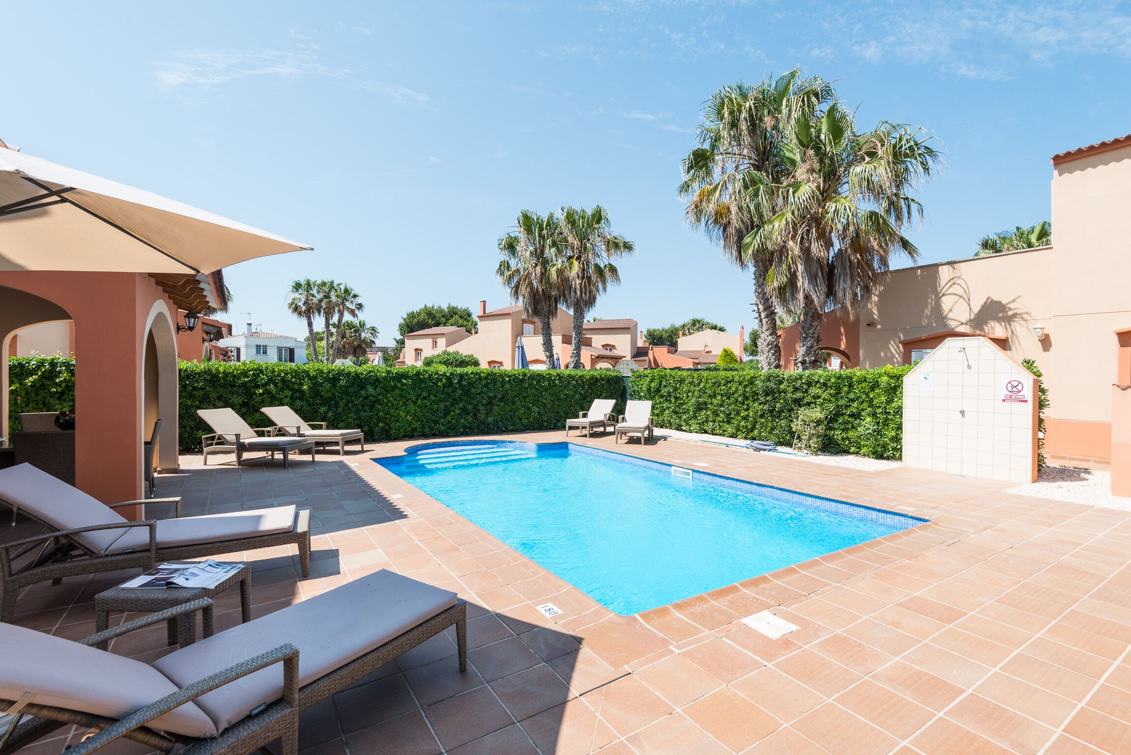 Una piscina con sillas de descanso y una zona de estar techada.