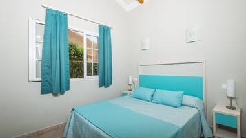 A bedroom with a bed, a nightstand, a window with curtains, and a ceiling light.