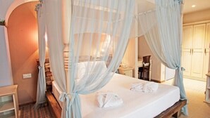 A bedroom with a canopy bed, a bedside table, a chair, and a wardrobe. - Igdeli Han Hotel (Cesme)