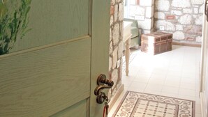 A room with a stone wall, a wooden door labeled "KEKİK ODASI", and a small wooden chest. - Igdeli Han Hotel (Cesme)