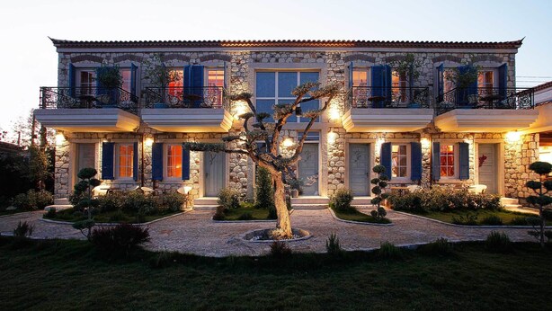 A stone building with multiple balconies and a well-lit entrance. - Igdeli Han Hotel (Cesme)